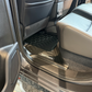 Black TPE floor mats installed in the rear of a vehicle, shown between grey seats.